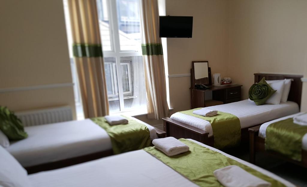 a room with three beds and a window at Hazelbrook House B&B in Dublin