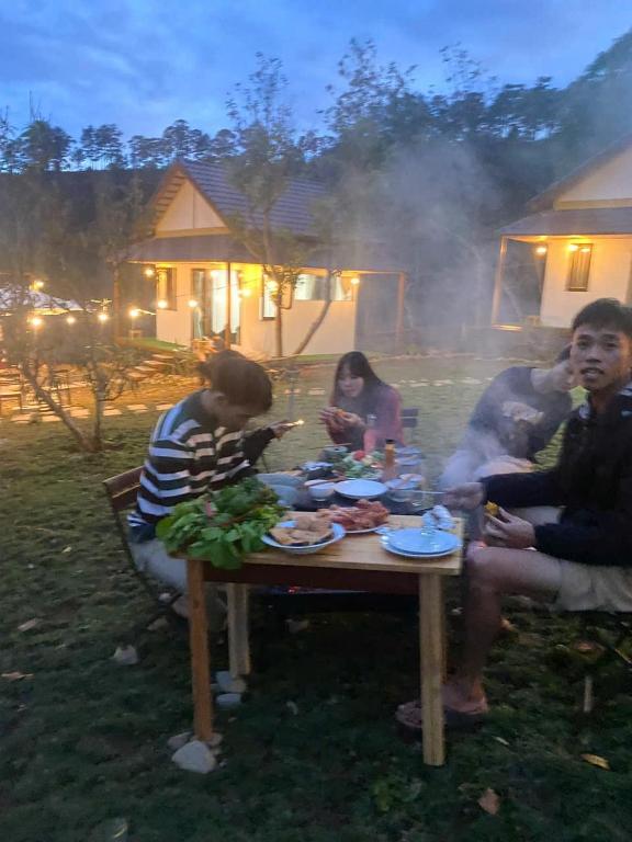 a group of people sitting around a table eating food at Đồi Lát Homestay in Da Lat