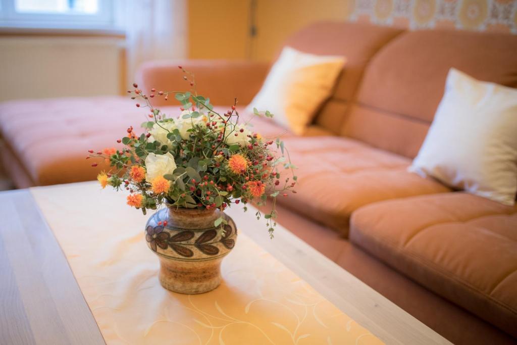 a vase with flowers on a table in front of a couch at Ferienwohnung "Beim Nachtwächter" in Görlitz