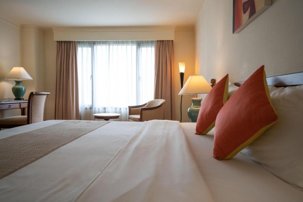 A close bedroom view focused on the large bed, red pillows, window, and nearby writing table.