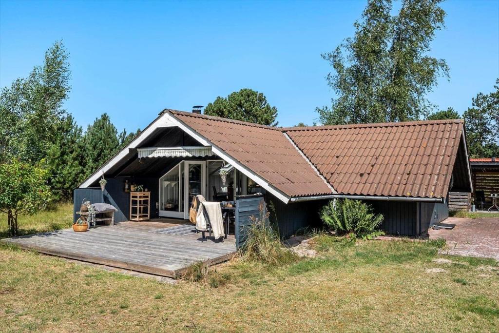 a black house with a wooden porch and a deck at M368-Rodby-Spurvevaenget-11 in Rødby