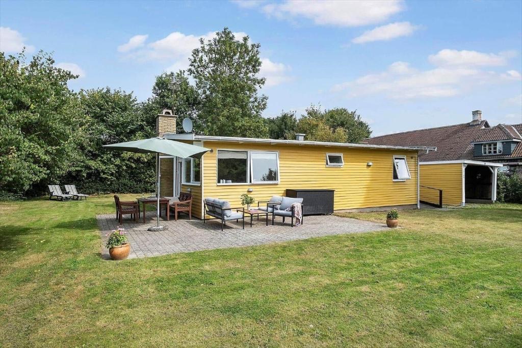 a yellow house with a patio and an umbrella at 1484-N-Gilleleje-Markvaenget-11 in Gilleleje