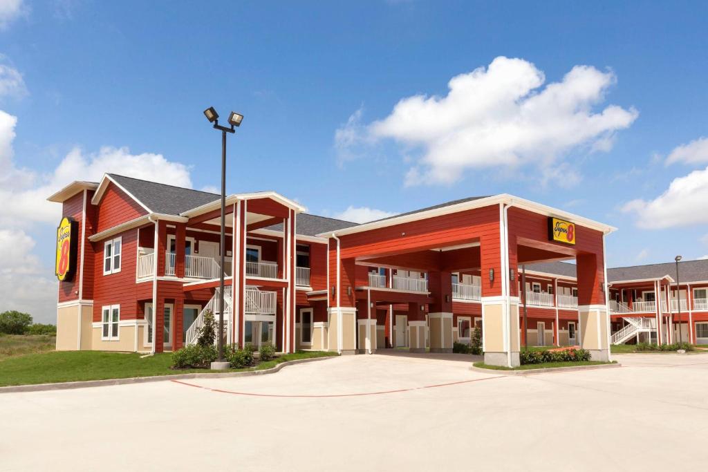 a large red building with a parking lot at Super 8 by Wyndham Carrizo Springs in Carrizo Springs