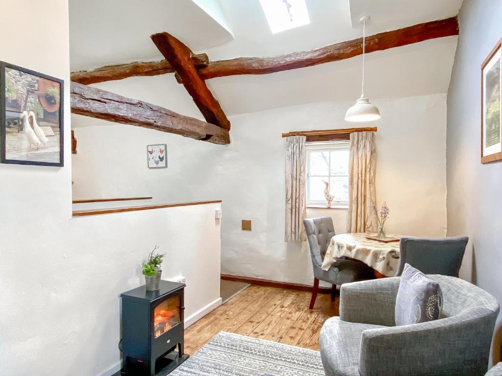 a living room with a fireplace and a table at Rebecca Puddle Duck Cottage in Bassenthwaite