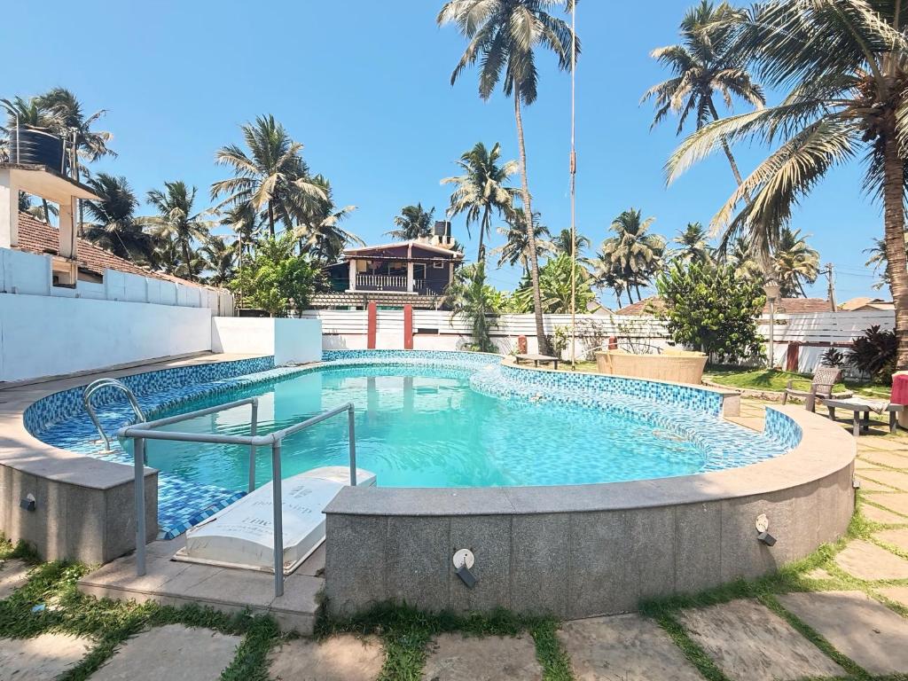 a swimming pool in a resort with palm trees at Red Sea Beach Resort in Anjuna