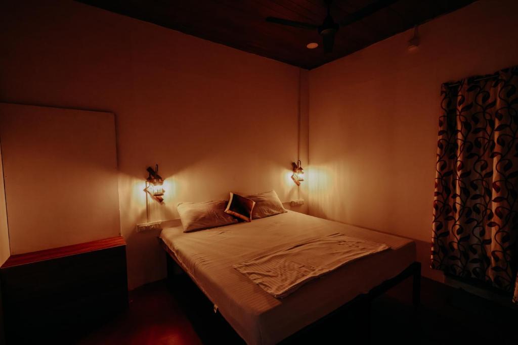 a bedroom with a bed with two lights on it at Marari Jackson Beach Homestay in Mararikulam