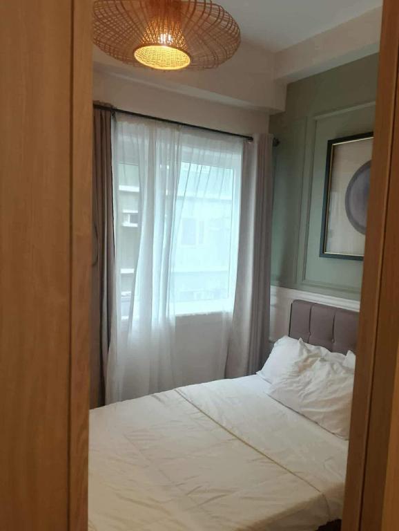 a bedroom with a white bed and a window at TuksHotel in Manila