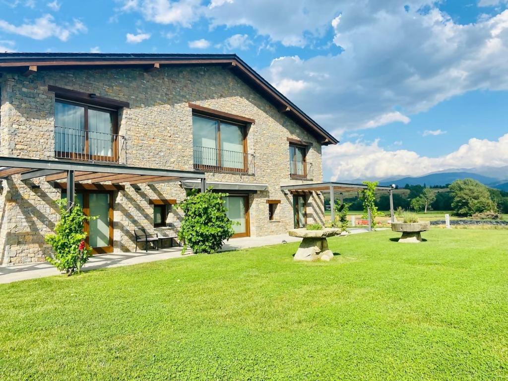 a stone house with a green lawn in front of it at Casa de 7 suites y vistas 360. Les Feixes Llargues in Bolvir
