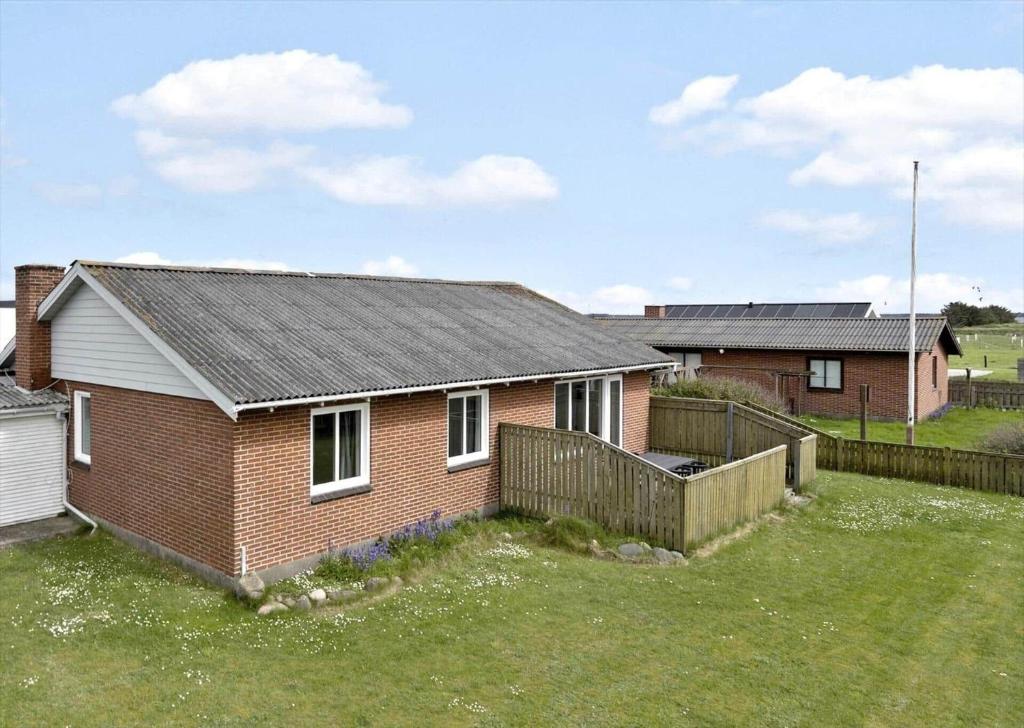 a brick house with a fence in a yard at 70099-Ulfborg-Klitrosevej-2 in Ulfborg