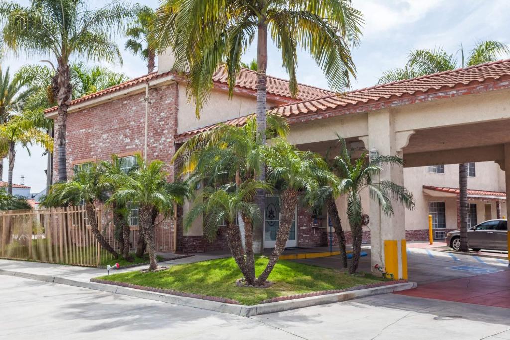 a building with palm trees in front of it at Days Inn & Suites by Wyndham South Gate in South Gate