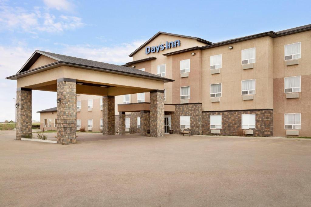 a hotel with a large parking lot in front of it at Days Inn by Wyndham Innisfail in Innisfail