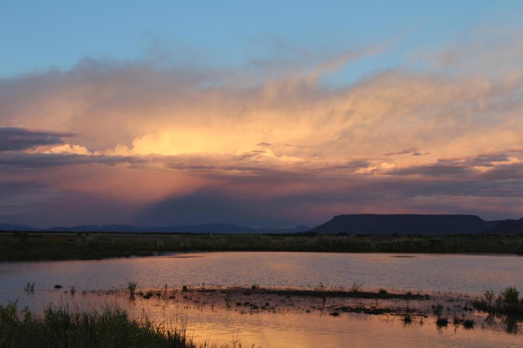 a sunset over a body of water with a rainbow at Beaconsfield Farm in Hofmeyr