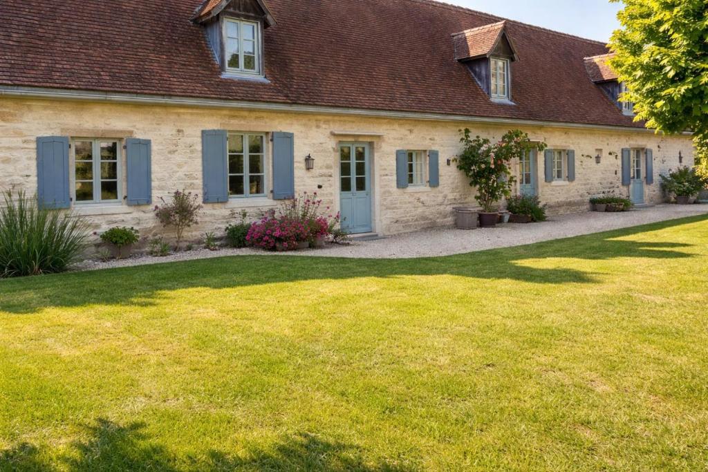 a house with blue shutters and a grass yard at La longère du golf in Verneuil-sur-Indre