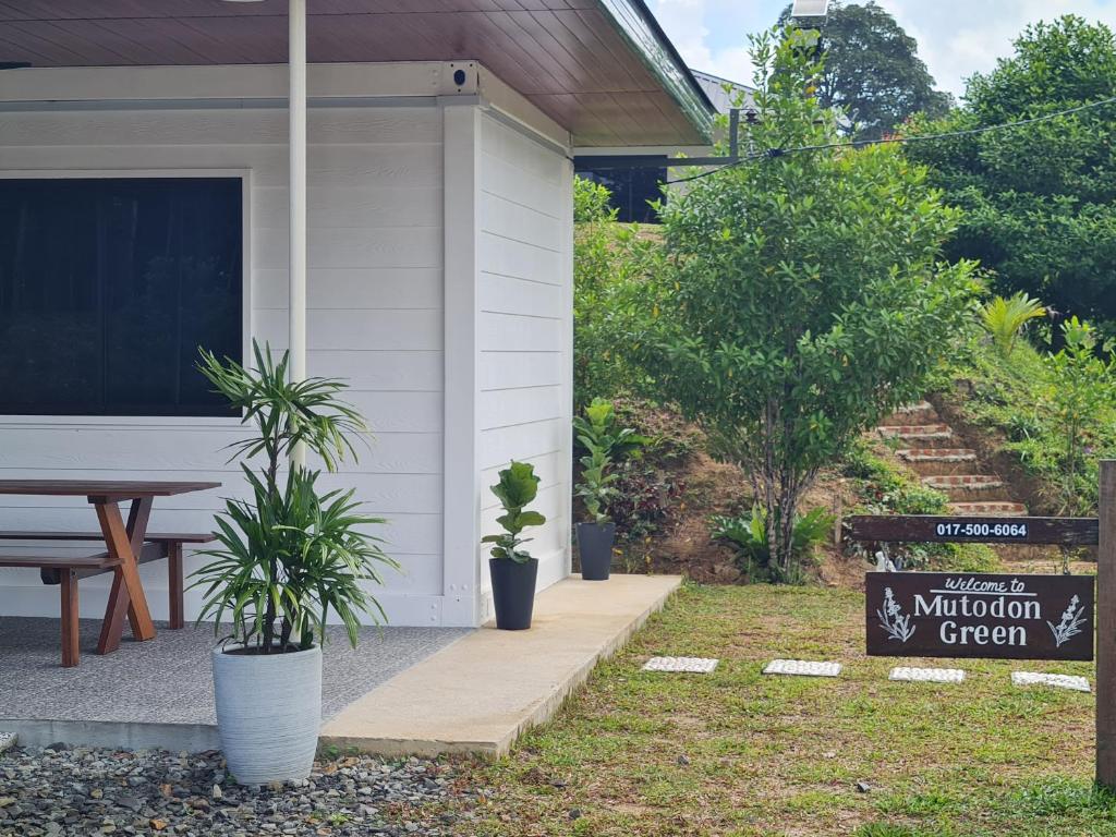 a porch of a house with a sign and plants at Mutodon Green in Kuala Penyu