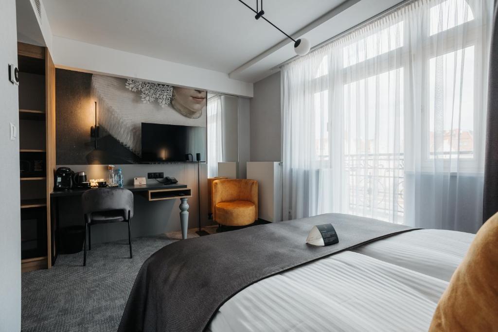 a bedroom with a bed and a desk and a television at Hotel M4 Boutique in Krakow
