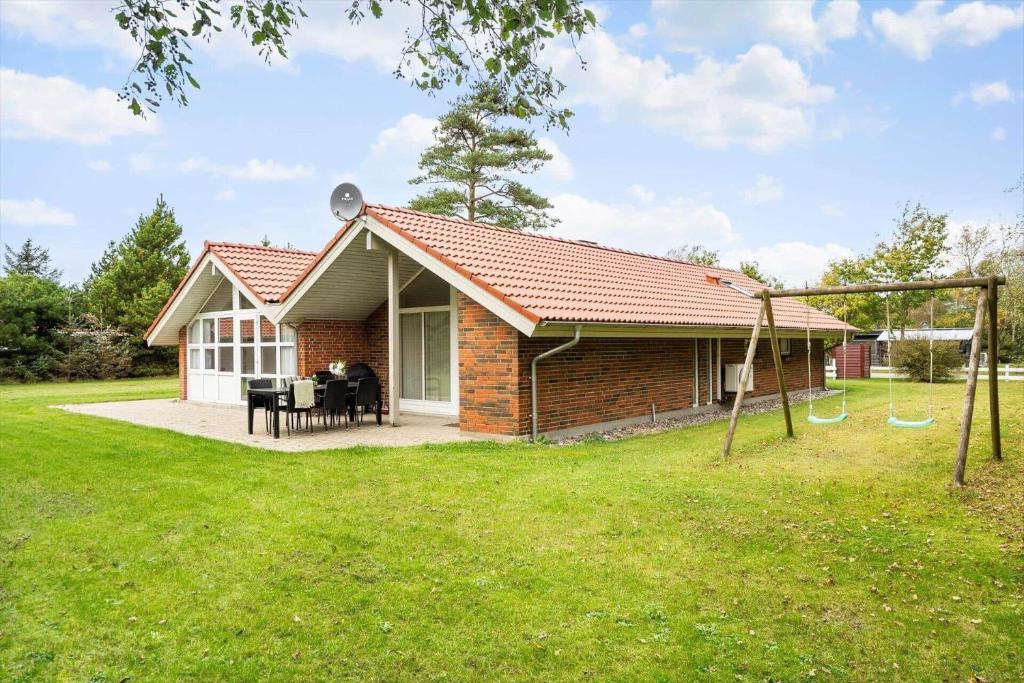a small brick house with a playground in the yard at 30705-Ulfborg-Valmuevej-288 in Ulfborg