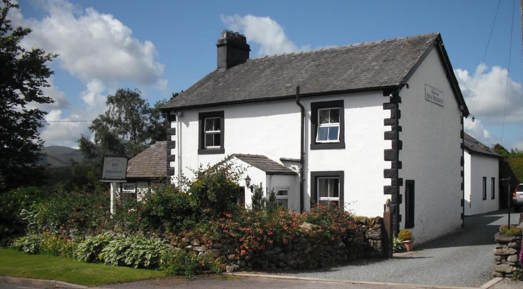 una casa blanca con flores delante en Netherdene Country House Bed & Breakfast, en Troutbeck