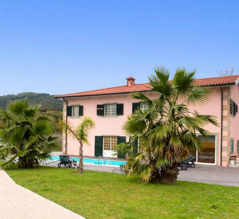 a pink house with palm trees in front of it at Préfacio Do Silêncio in Godinhaços