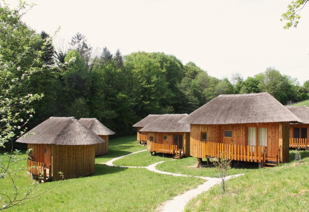 a group of wooden huts in a field at Glamping Bionic healing village in Slovenska Bistrica