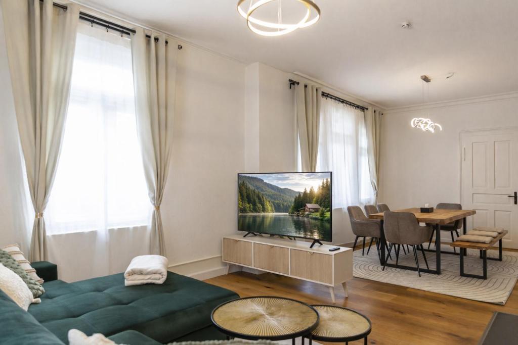 a living room with a couch and a tv and a table at Charaktervolle 122qm Altbau-Ferienwohnung mit Stuck, viel Platz für Familien & Gruppen bis zu 8 Personen, Parkplatz inklusive in Baiersbronn