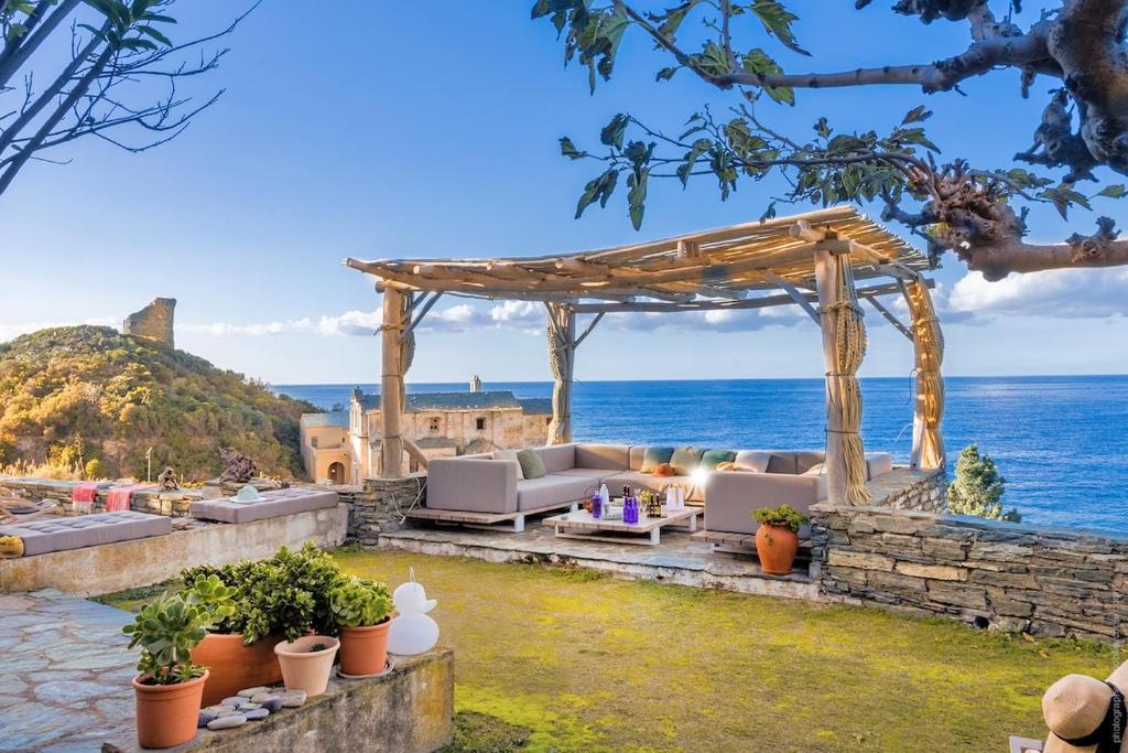 an outdoor seating area with a pergola and the ocean at Villa MARION bord de mer in Pino