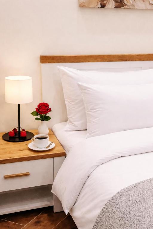 a bed with a table with a cup and a flower on it at Apartman Aurelia in Sremska Mitrovica