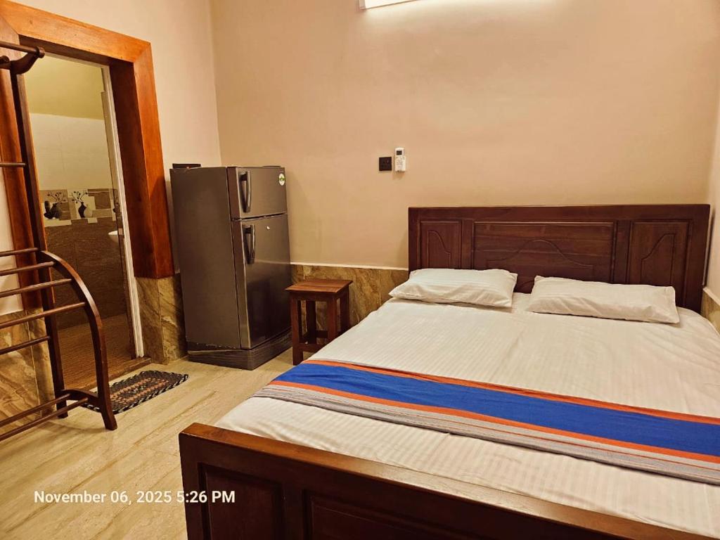 a bedroom with a large bed and a refrigerator at AJk villa in Negombo