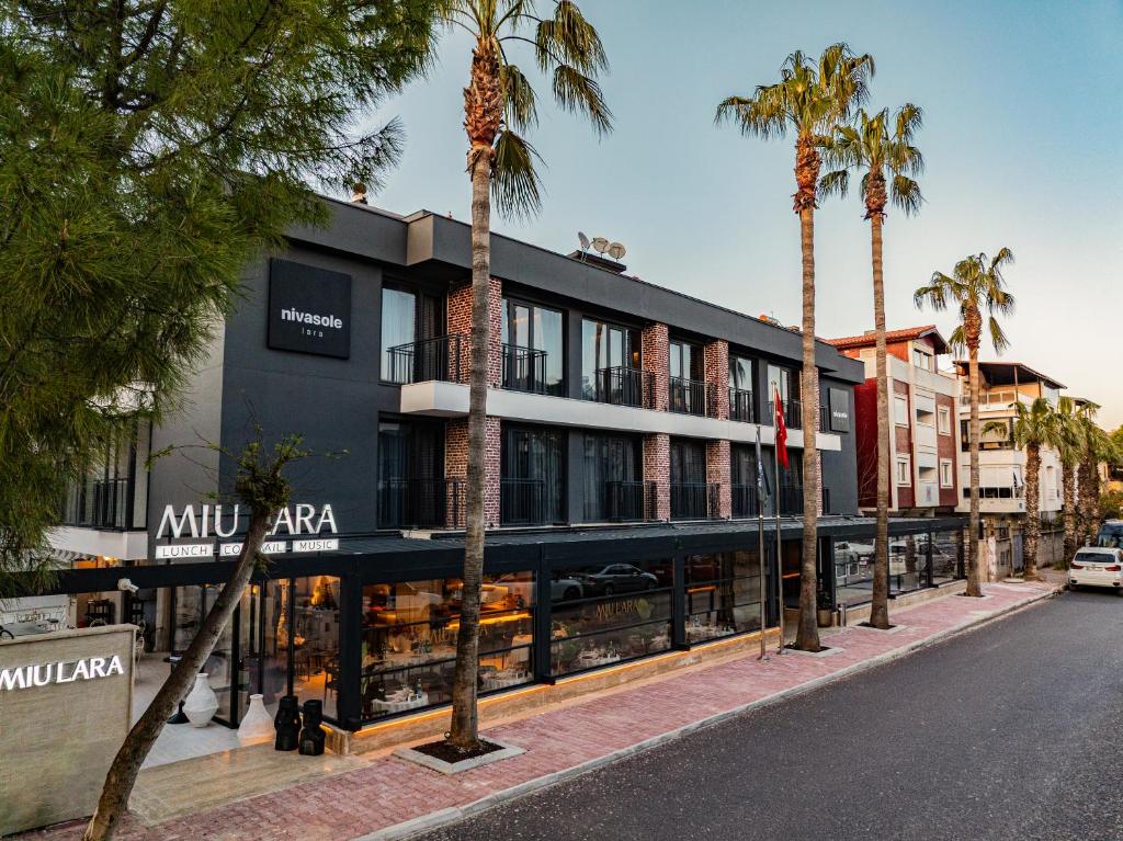 a building with palm trees in front of a street at Nivasole Lara Pure Comfort & Style in Antalya