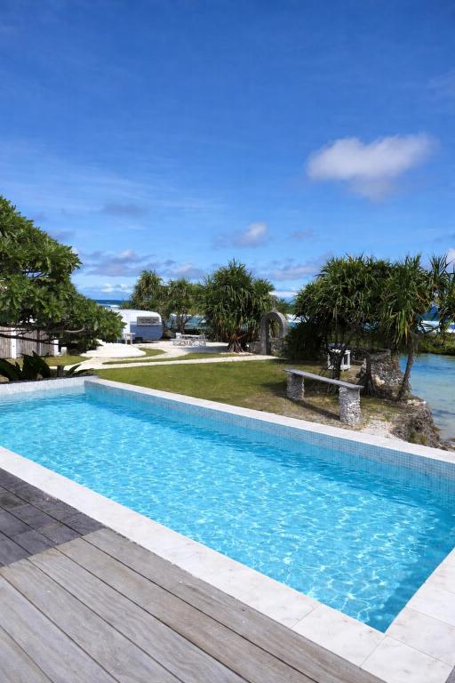 a swimming pool with a wooden deck next to the water at My Island Home Vanuatu in Eton