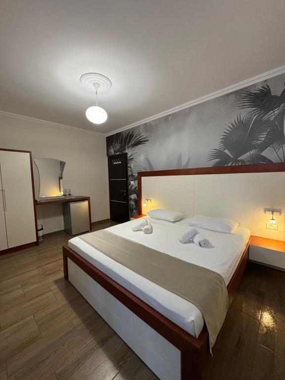 a bedroom with a large bed with white sheets at Mesdheu ApartHotel in Durrës