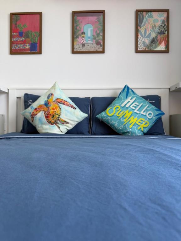 a bed with blue sheets and pillows on it at Mai Khao 777 Beach Condo in Ban Mai Salae