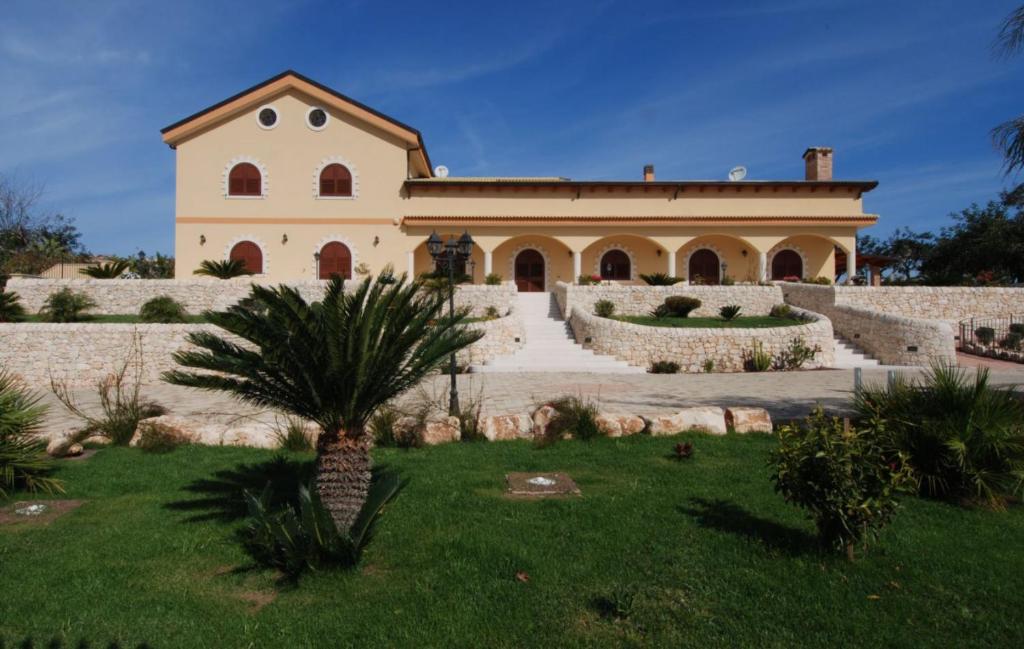a building with a palm tree in front of a yard at Villa Giulia - Sicilian Luxury Garden in Punta Secca