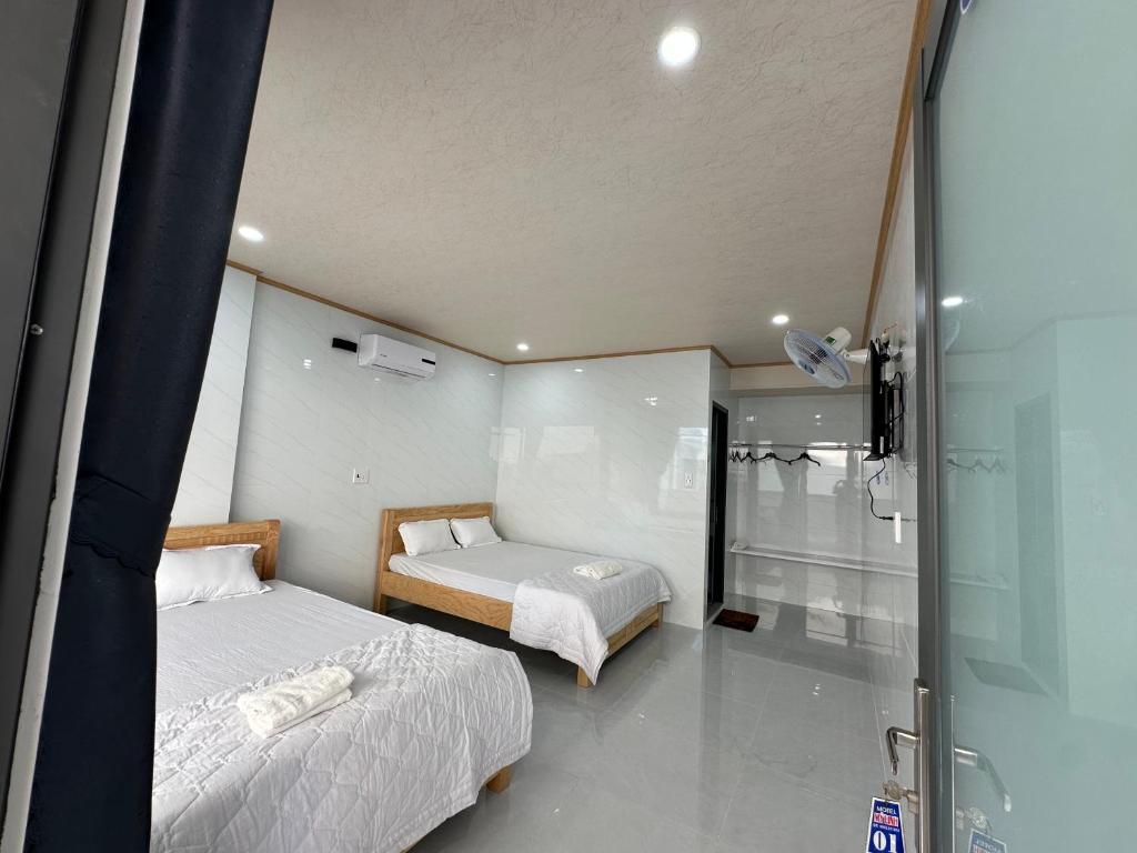 a bedroom with two beds and a glass shower at Motel Mỹ Linh 976 in Long Hai