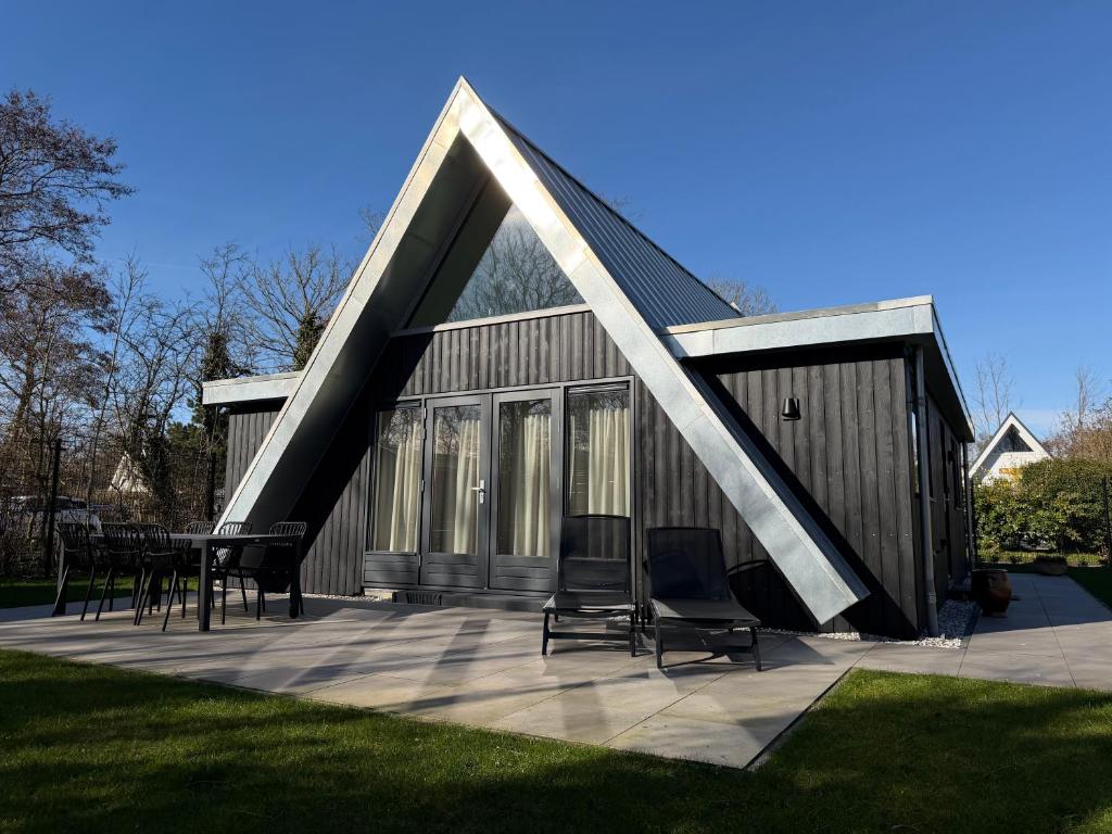 a house with a triangular roof with chairs on a patio at Vakantiehuis Lucky in Ons Belang