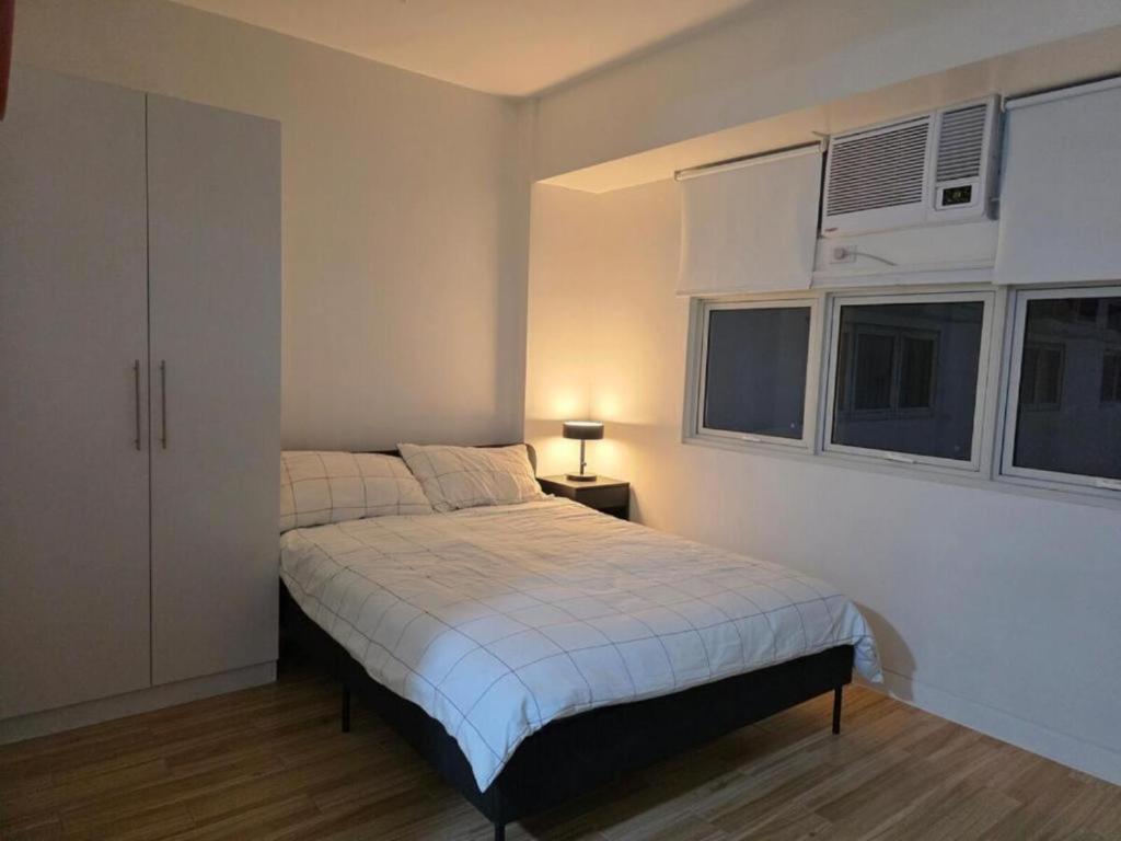 a bedroom with a bed and two windows at Cozy Studio Long Stays Welcome in Biñan