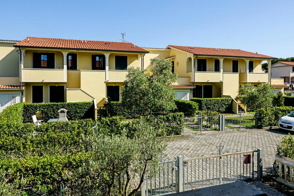 een geel huis met een hek ervoor bij Villetta Dino in Vada