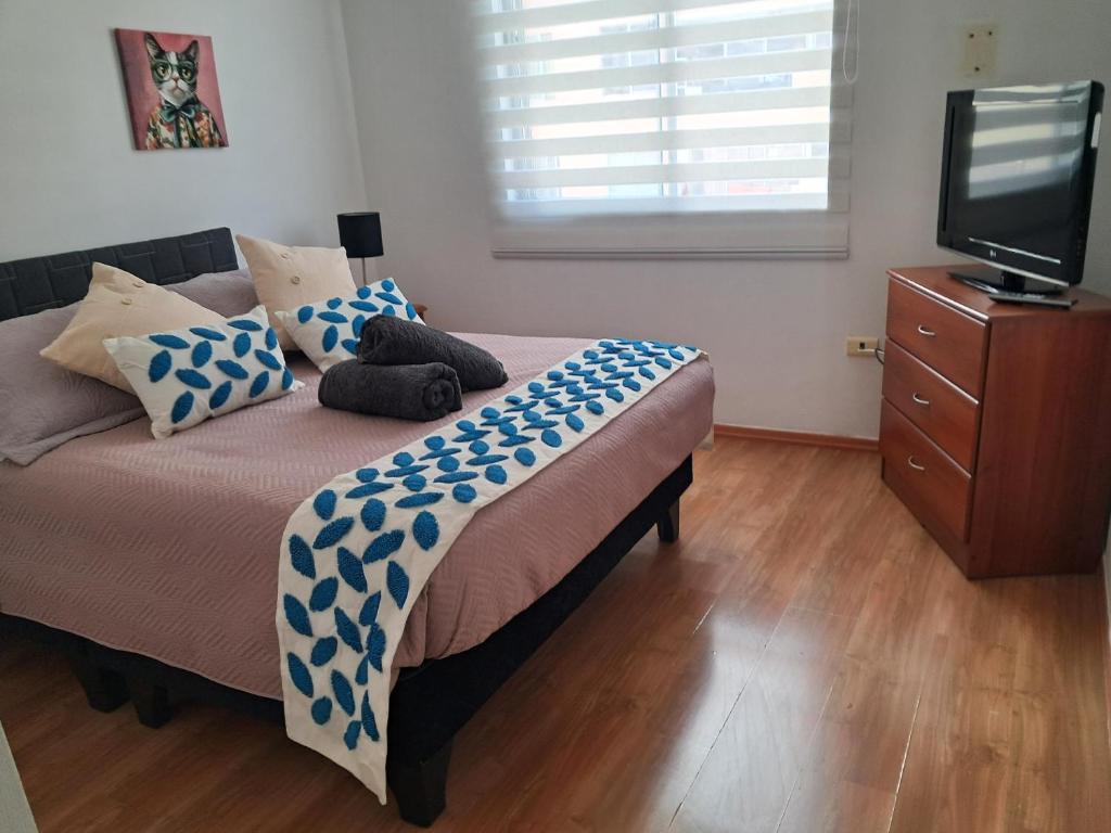 a bedroom with a bed with blue and white pillows at Moderno Depto 1D con Estacionamiento Gratis Ideal Trabajo in Antofagasta