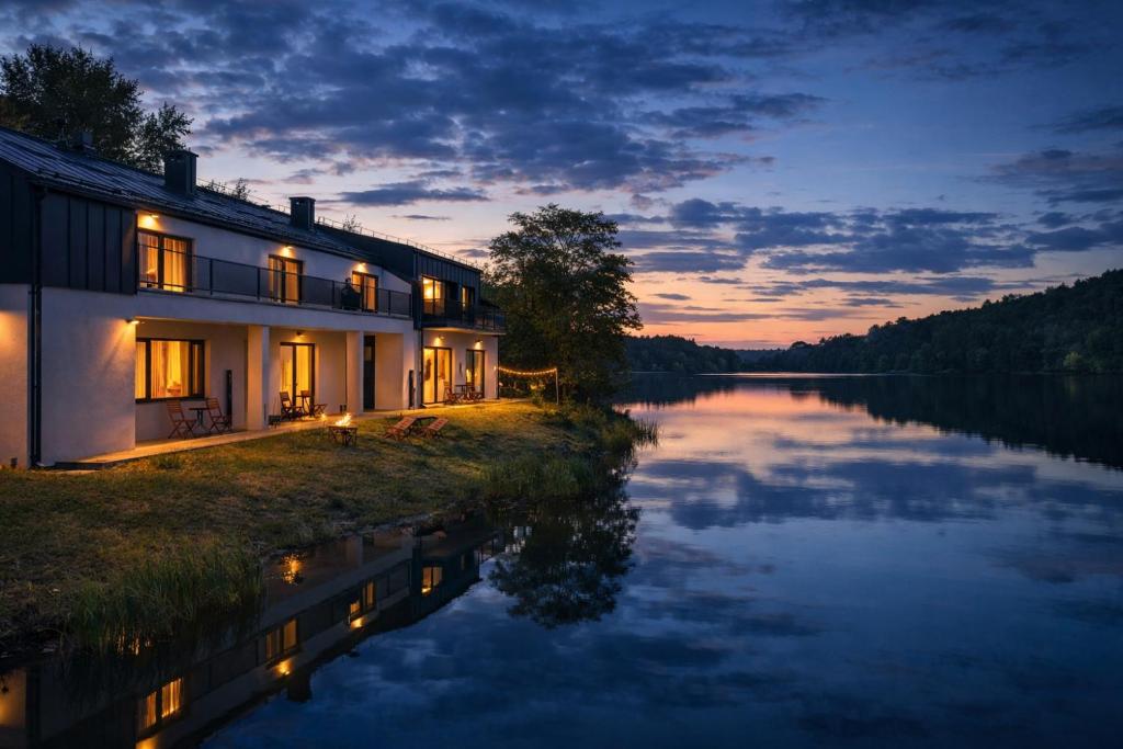 a house on the shore of a lake at night at LAKE VIEW Apartamenty in Brodnica