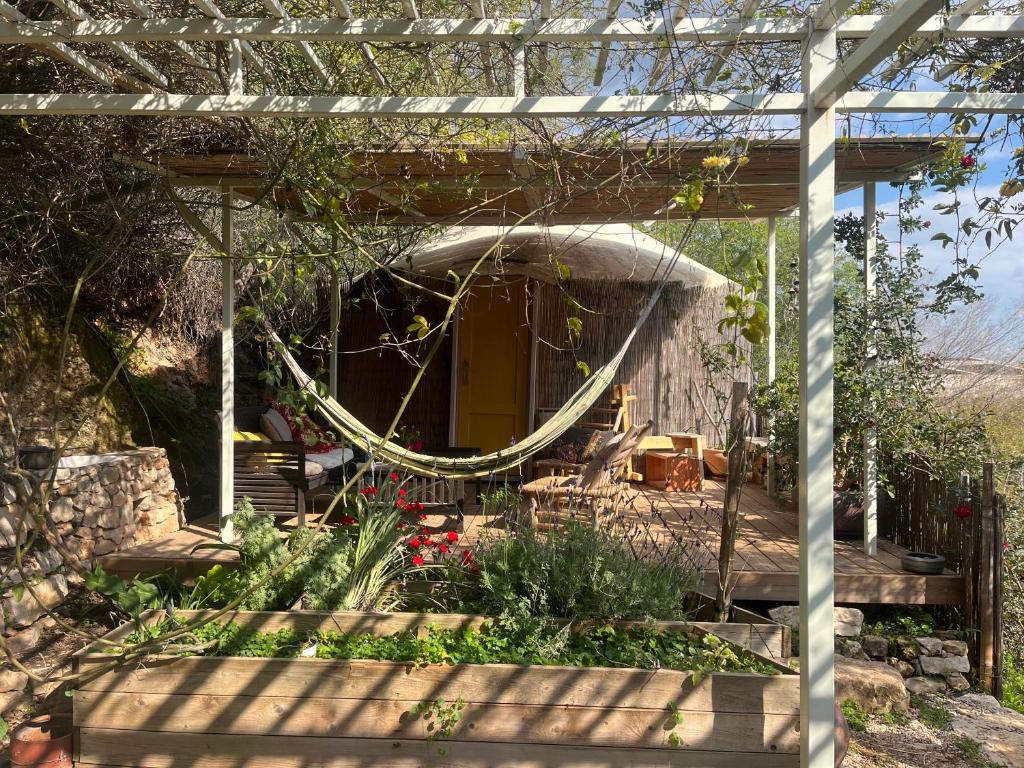 a pergola with a gazebo in a garden at Meek Yurt in Yodefat