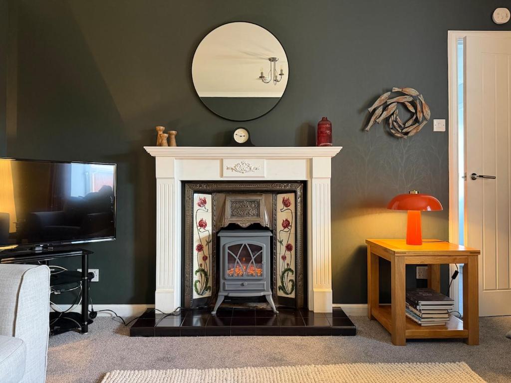 a living room with a fireplace and a mirror at Heatherlea Cottage in Skigersta