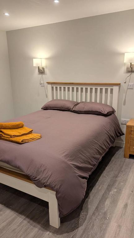 a large bed in a bedroom with two lights on the wall at Polbarrow in Ruan Minor