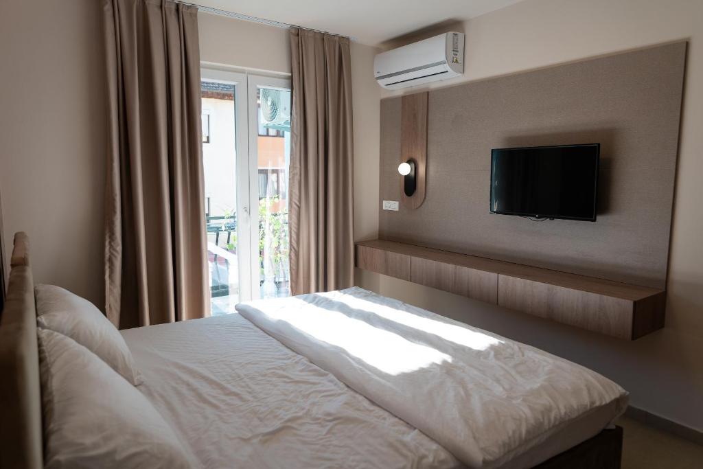 a bedroom with a bed and a tv on the wall at Dremka Guesthouse Peshtani in Ohrid