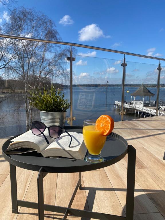 a table with a glass of orange juice and a book at Apartament MoLoo II in Ostróda