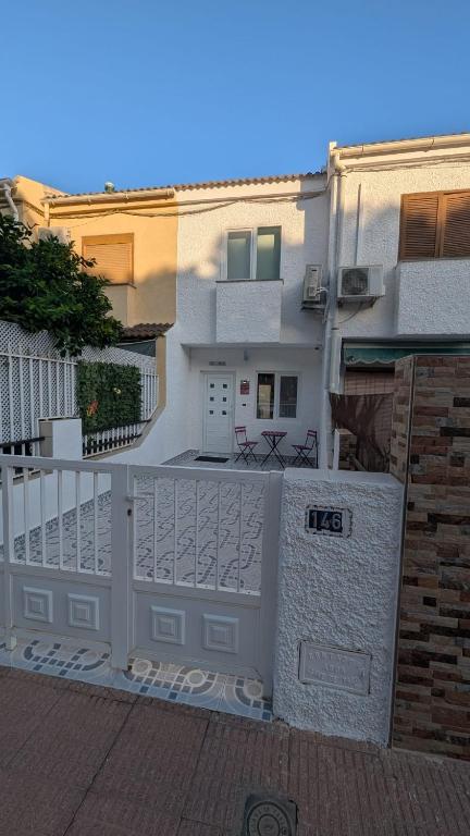 a white house with a white fence and a building at Casa Ursula in Los Alcázares