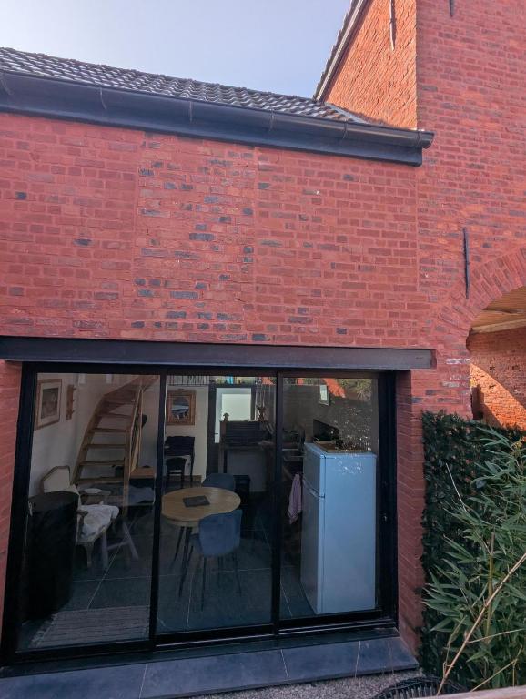 a brick building with glass windows and a table at Le Pigeonnier in Rosult