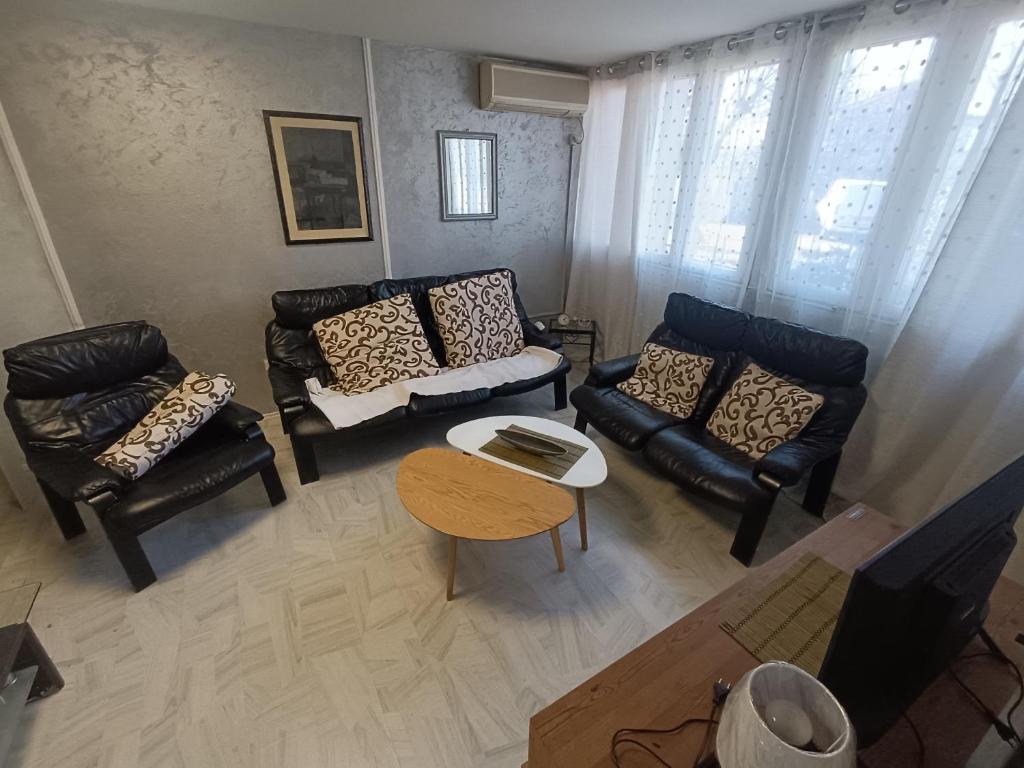 a living room with black leather couches and a table at Jela - Spacious Two-Bedroom Apartment near City Center with Free Parking & Wi-Fi in Podgorica