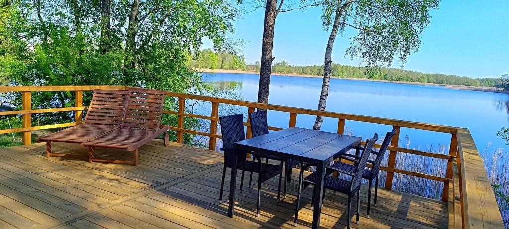 a wooden deck with a table and chairs next to a lake at BEJOT domki nad jeziorem in Wysoki Most