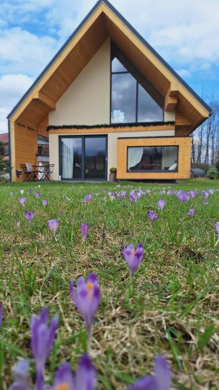 a house with purple flowers in the grass at Siedlisko DoReMiDo-mki "bez barier" SPA in Dzianisz