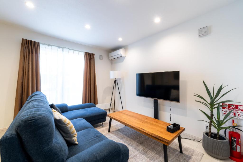 a living room with a blue couch and a tv at Nomad Stay Chitose in Chitose