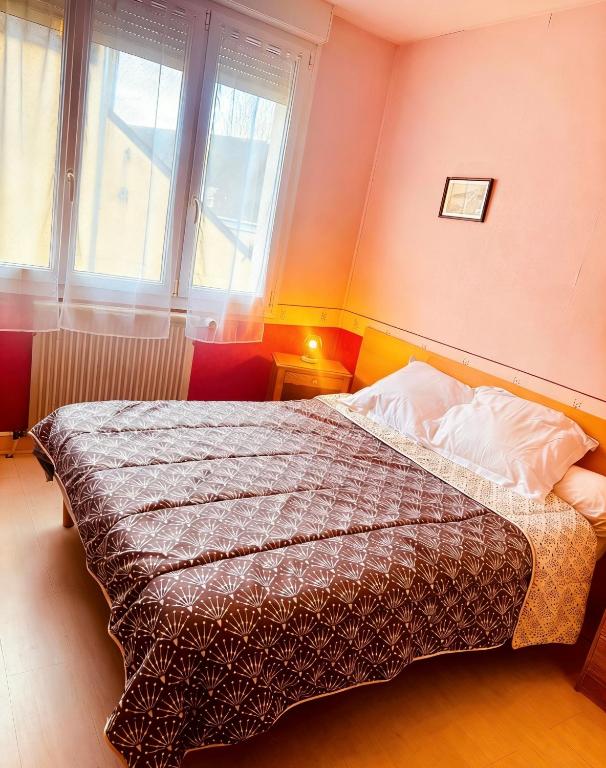a bedroom with a bed in a room with two windows at Hostellerie de la juhel in Villaines-la-Juhel